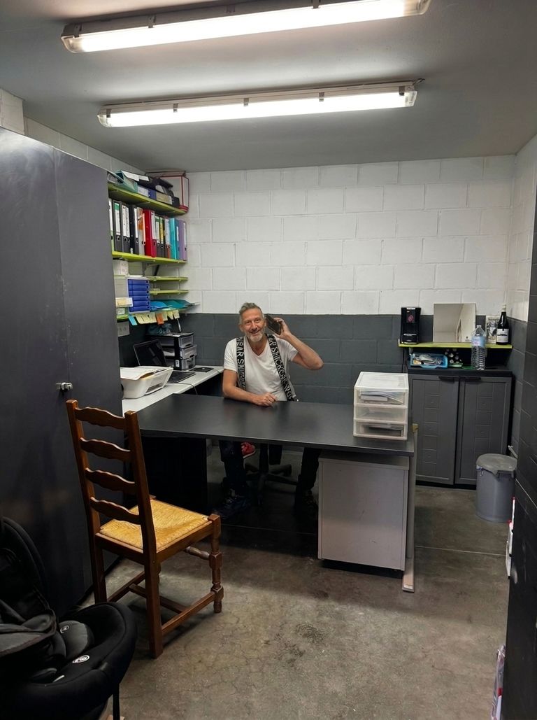 Edouardo Ricciolini au téléphone à son bureau, les classeurs de dossiers rangés derrière lui.